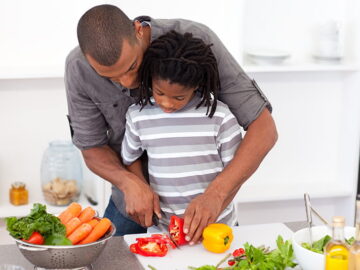 Father-son-cutting-vegetables-in-kitchen
